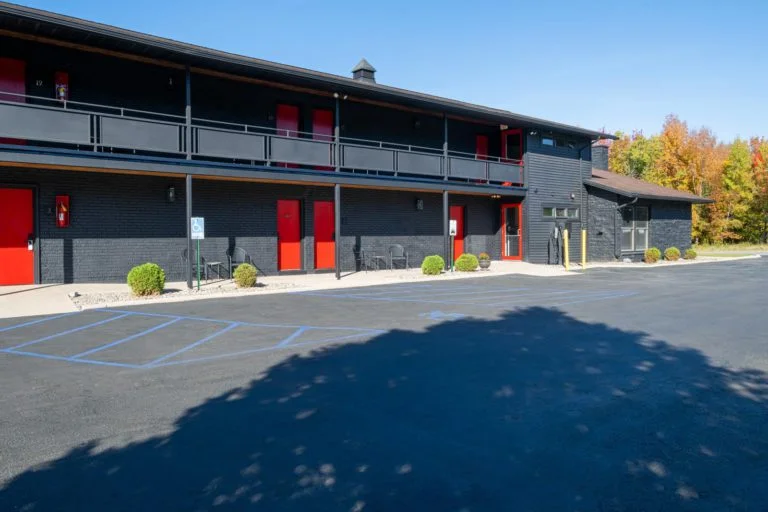 A black building with red doors and a parking lot.