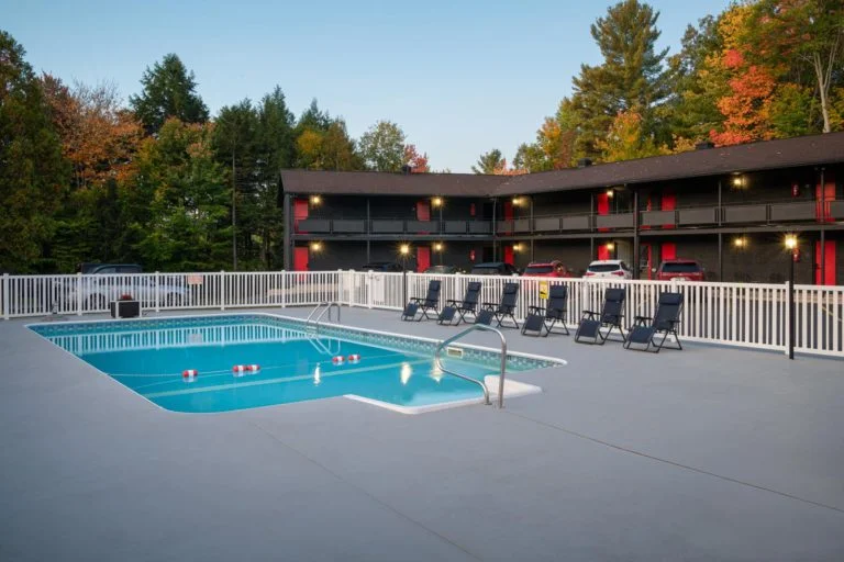 A motel with a swimming pool and lounge chairs.