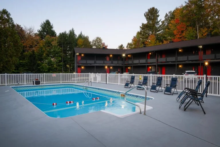 A swimming pool at a motel in a wooded area.