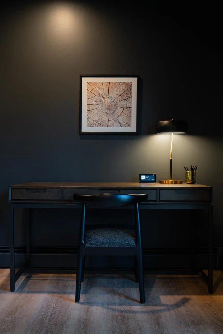 A desk in a room with black walls.