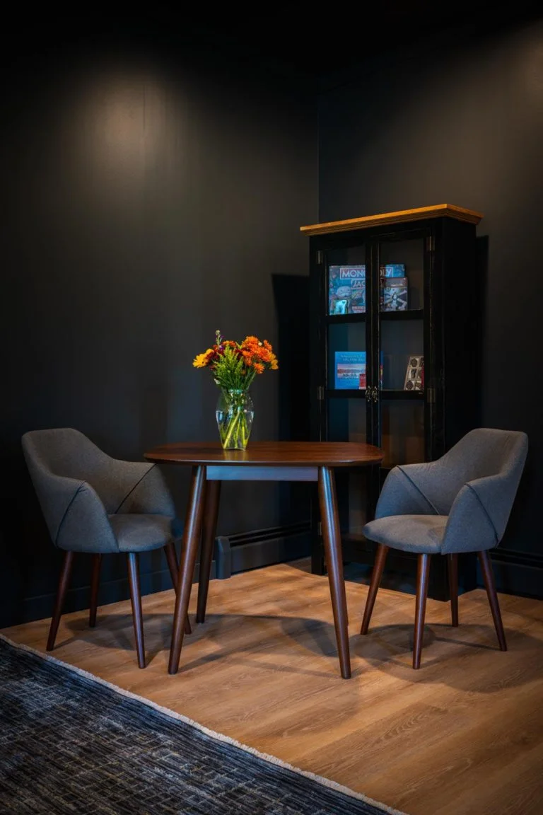 Two chairs and a table in a room with black walls.