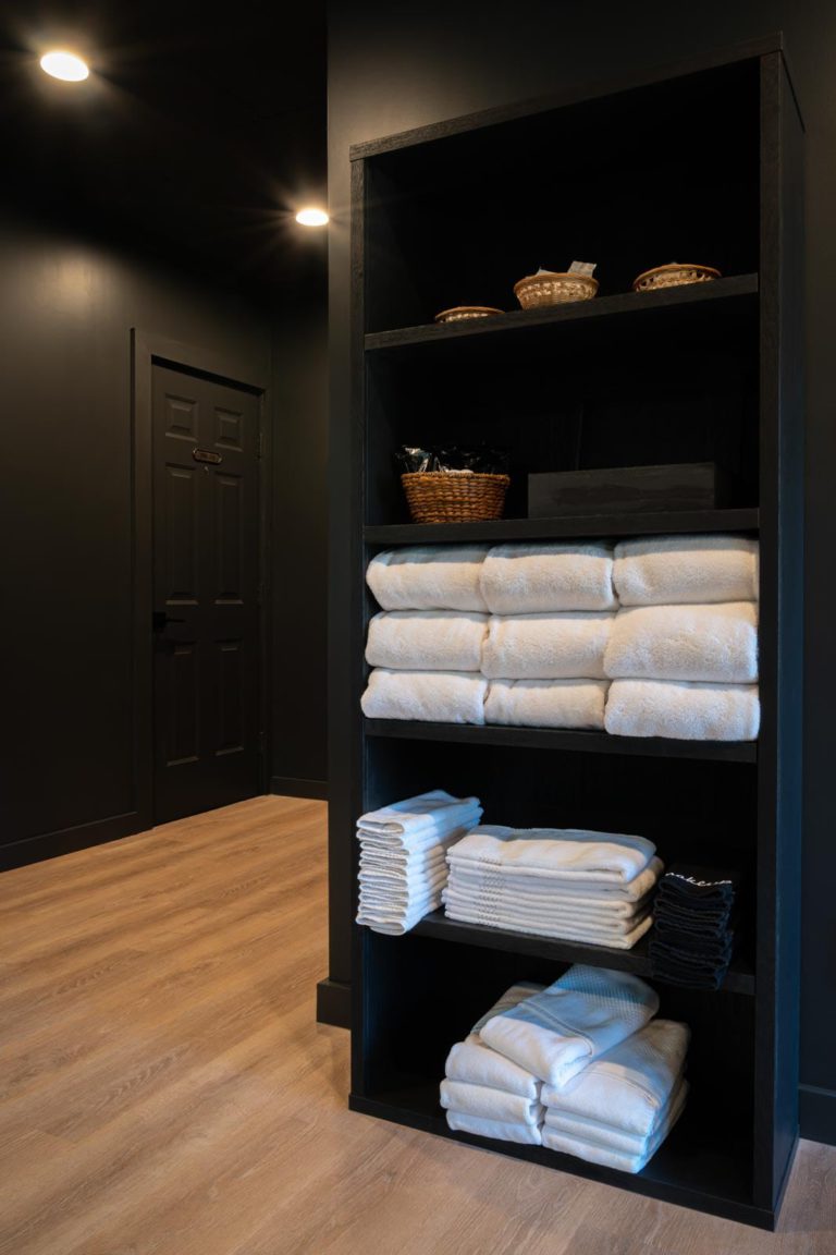 A black shelf with white towels on it.