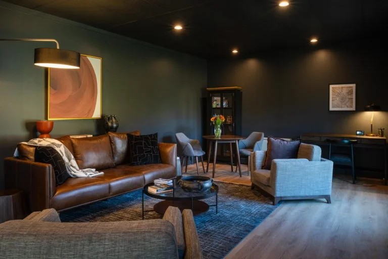 A living room with black walls and leather furniture.