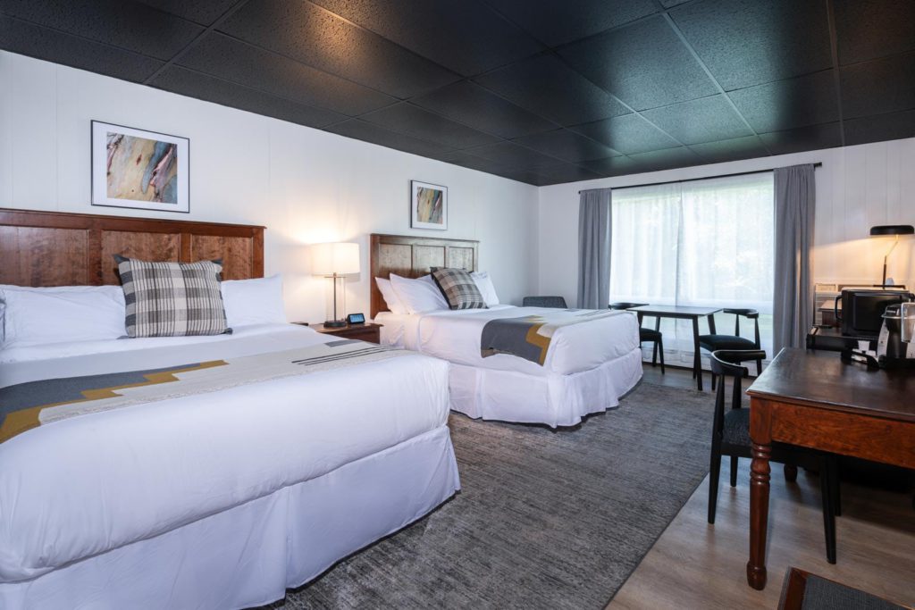 A hotel room with two beds and a desk.