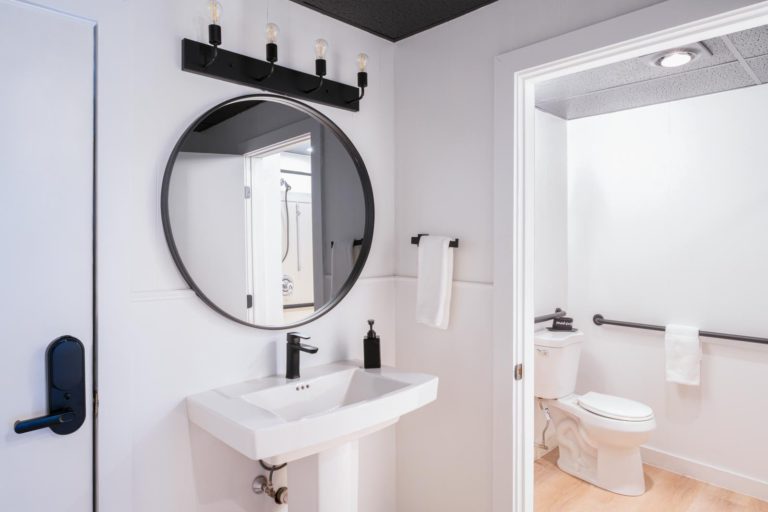A black and white bathroom with a round mirror.