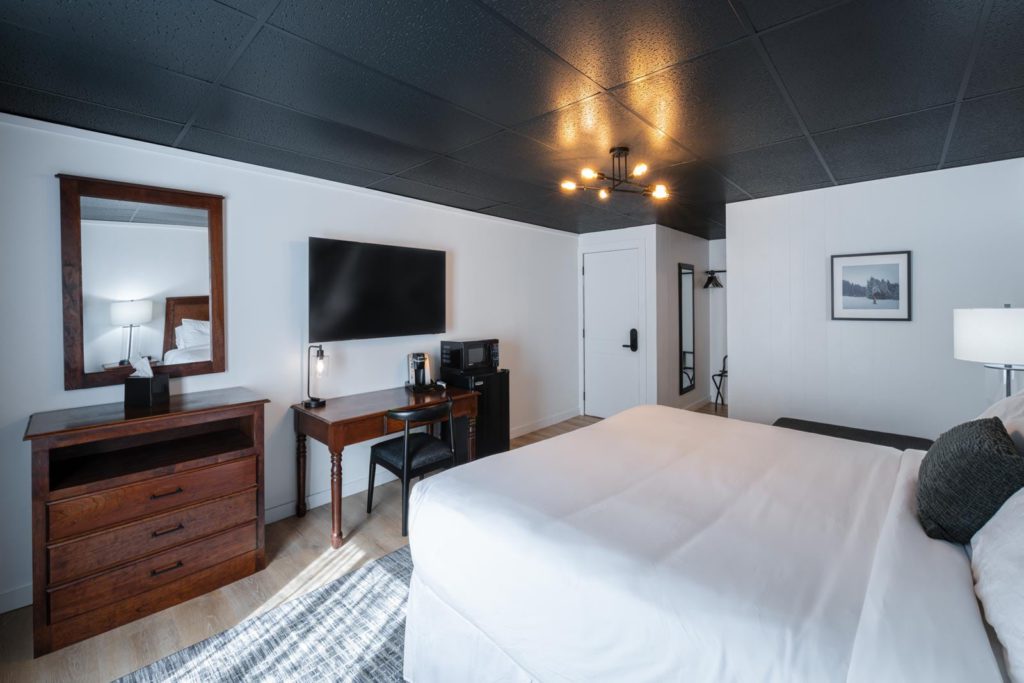 A room with a bed, dresser and tv.