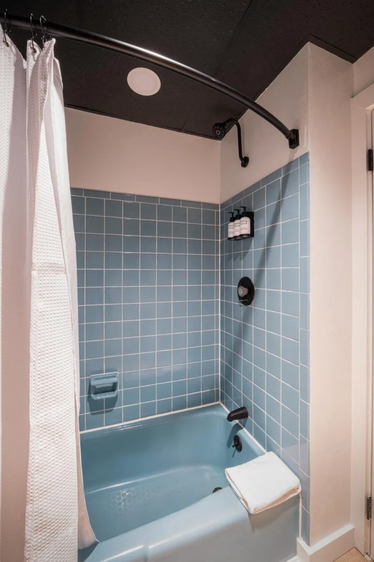 A bathroom with a blue tiled tub and shower.