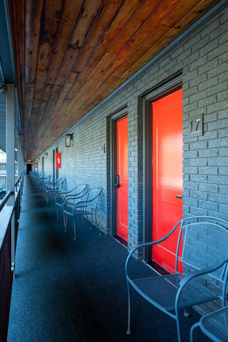 A row of chairs in a hallway with red doors.