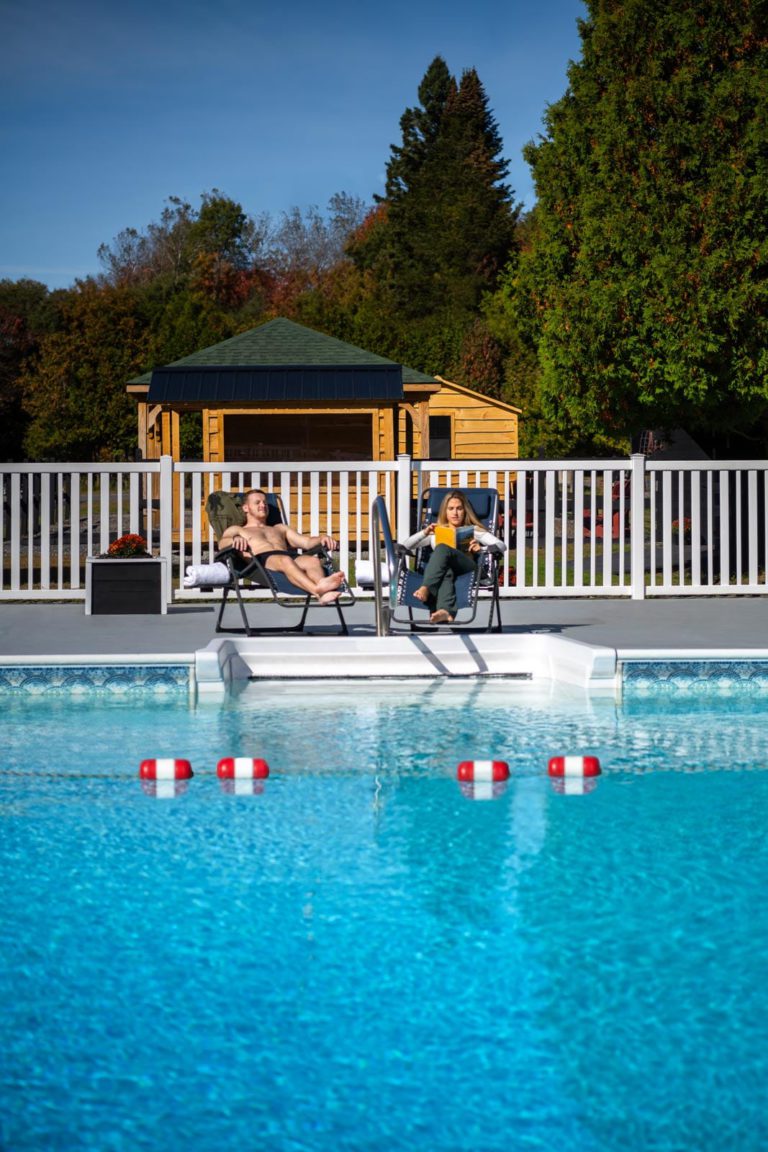 Two people sitting in chairs next to a swimming pool.