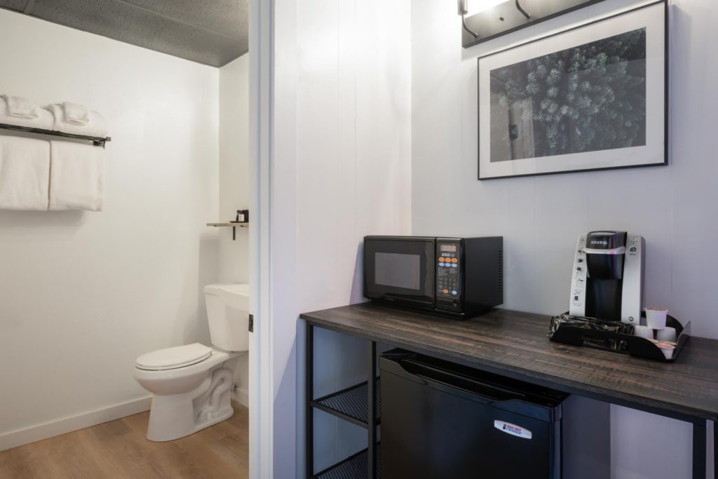 A small bathroom with a microwave and refrigerator.