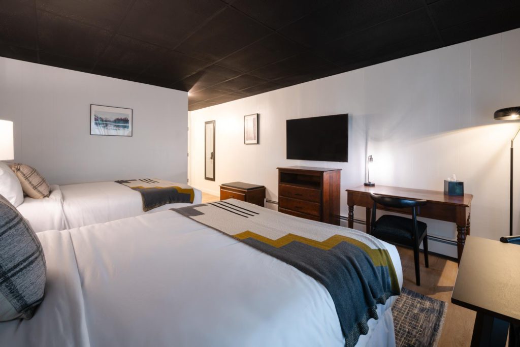 A room with two beds and a desk.
