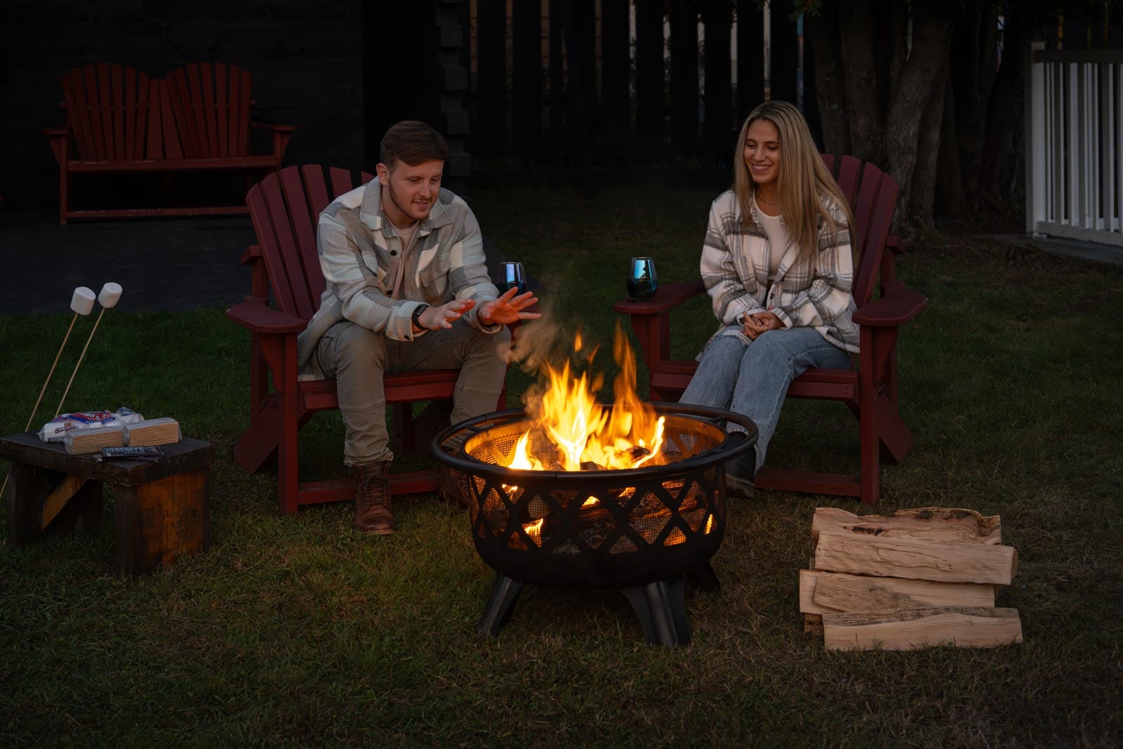 Two people sitting around a fire pit.