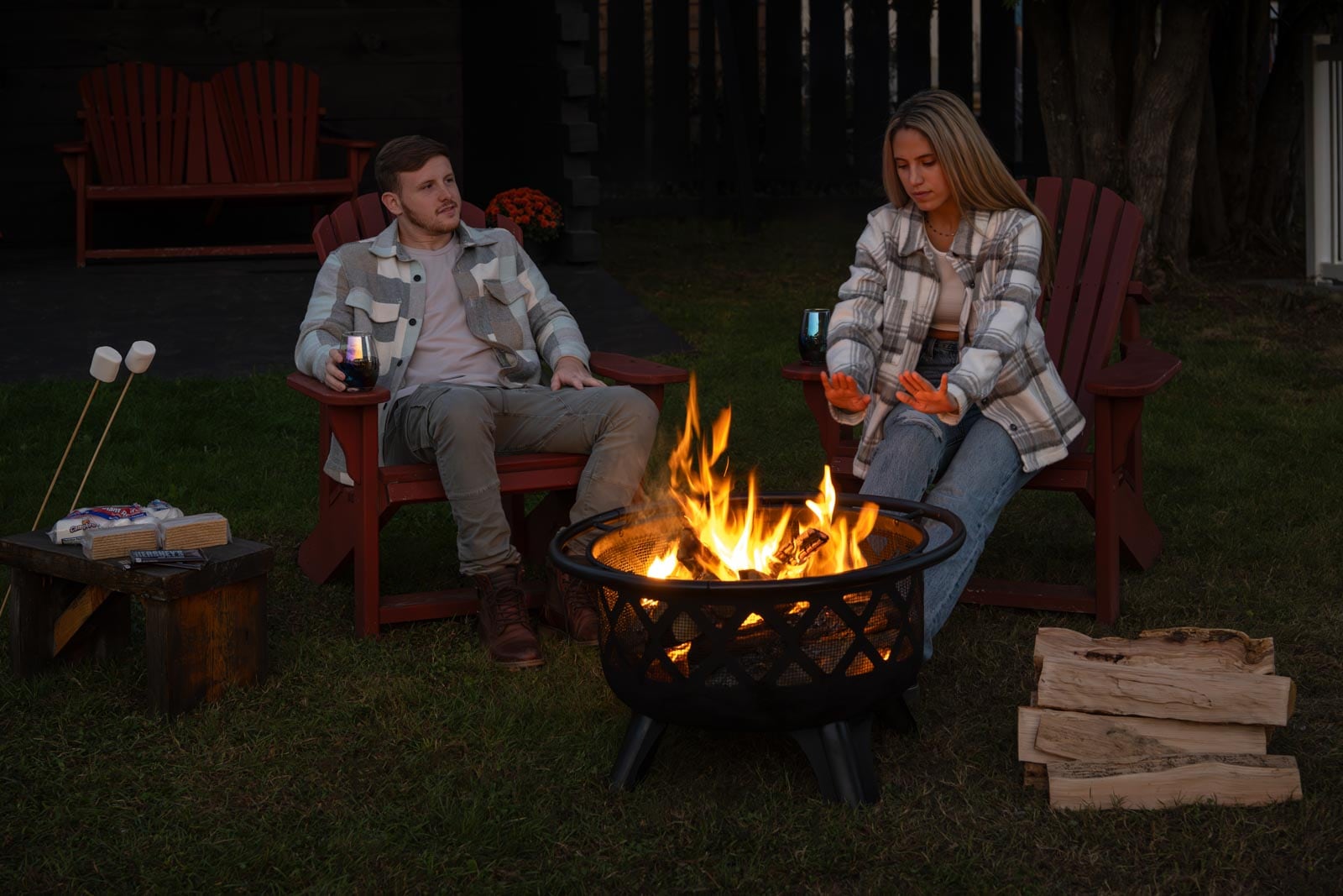 Two people sitting around a fire pit.