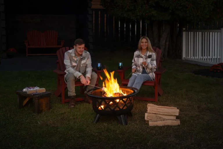 A man and woman sitting in chairs next to a fire pit.