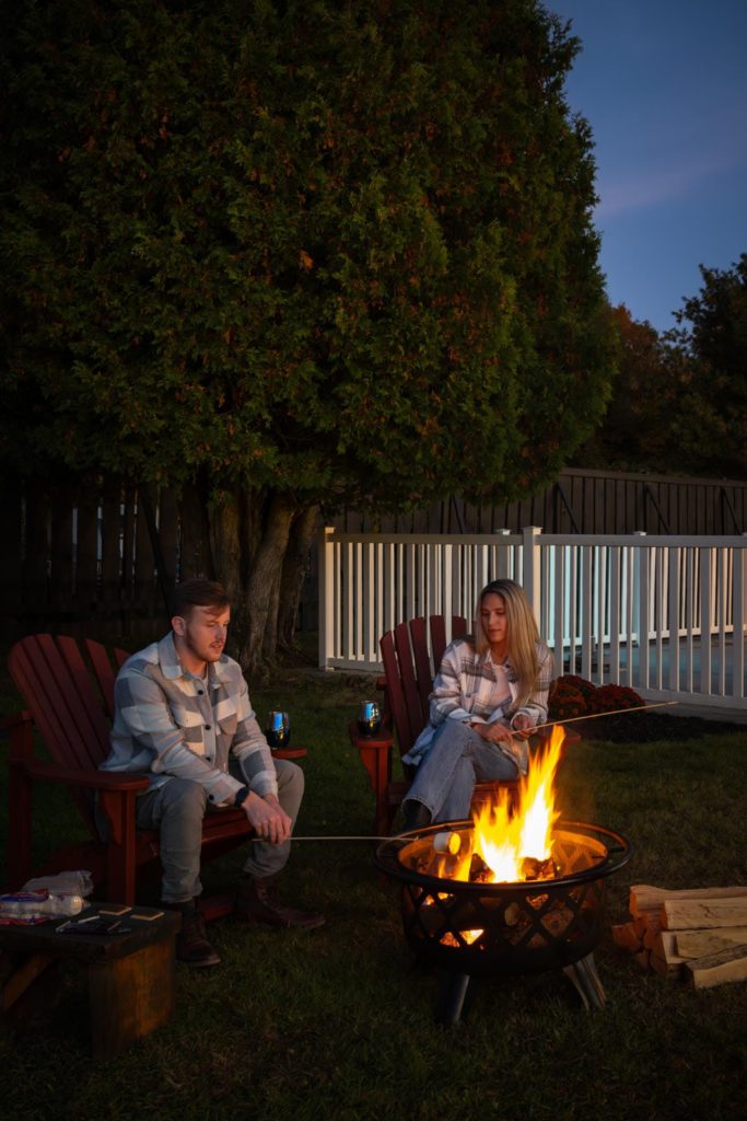 Two people sitting around a fire pit.