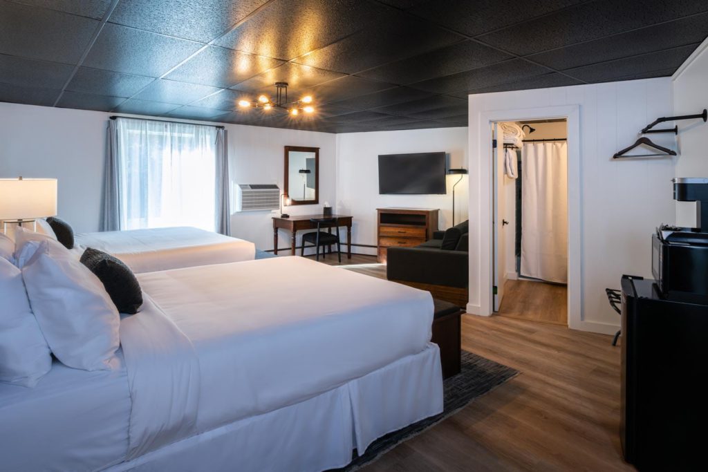 A hotel room with two beds and a television.