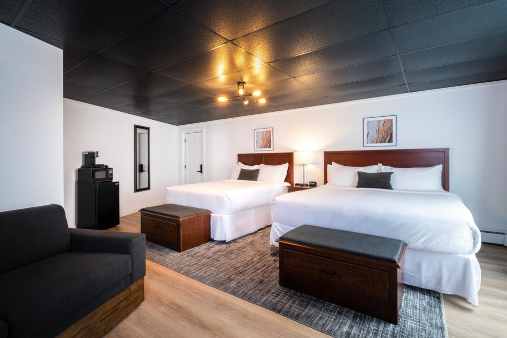A hotel room with two beds and a couch.